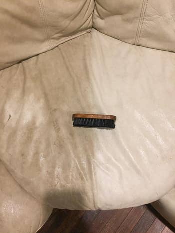leather brush in the middle of a cushion half treated with the product, one side dirty and the other off-white