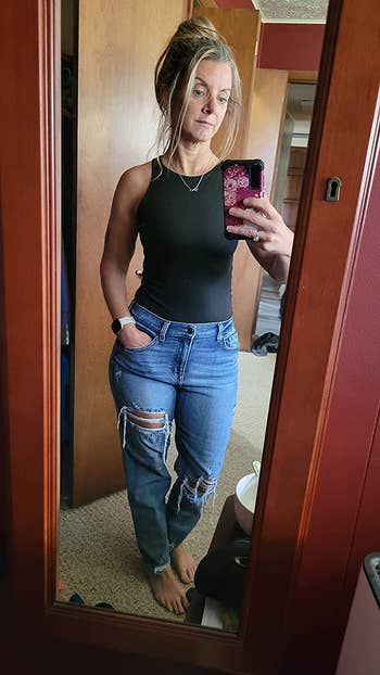 reviewer wearing bodysuit in black with ripped jeans