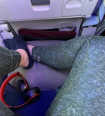A reviewer using the inflatable footrest on their flight