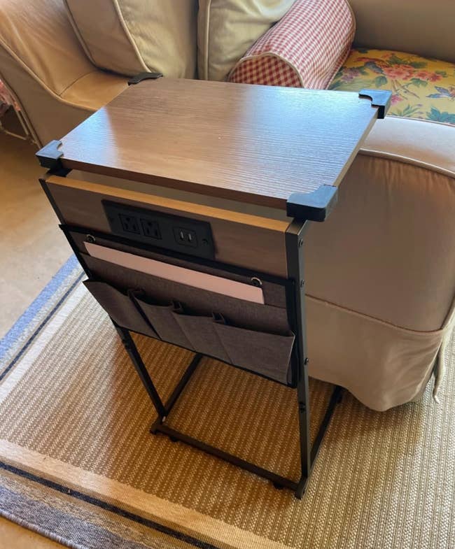 Side array with built-in powerfulness outlets and retention pockets, placed adjacent to a sofa. Perfect for organizing and charging devices