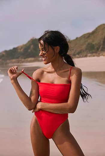 Model in lightly ruched red square neck strappy one piece 