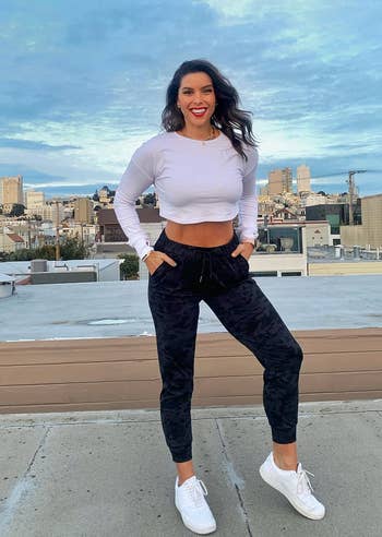 reviewer in white crop top and camo black joggers