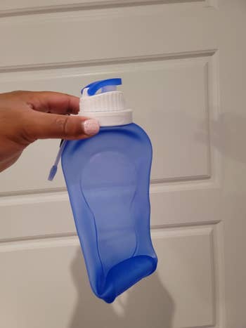 reviewer holding the empty unrolled blue water bottle