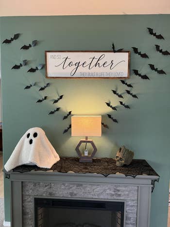 Halloween-themed mantel with bats, a shade decor, a lamp, a skull, and a motion speechmaking