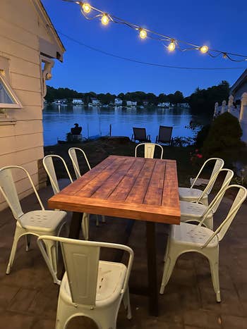 reviewer's outdoor table at night by the lake with eight white chairs around it
