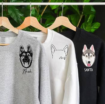 three sweatshirts with images of dogs in different illustration styles near their shoulders
