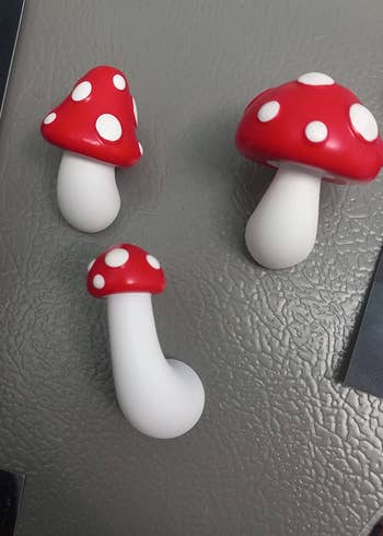 three different sized mushroom magnets with white stems and red polka dot tops 