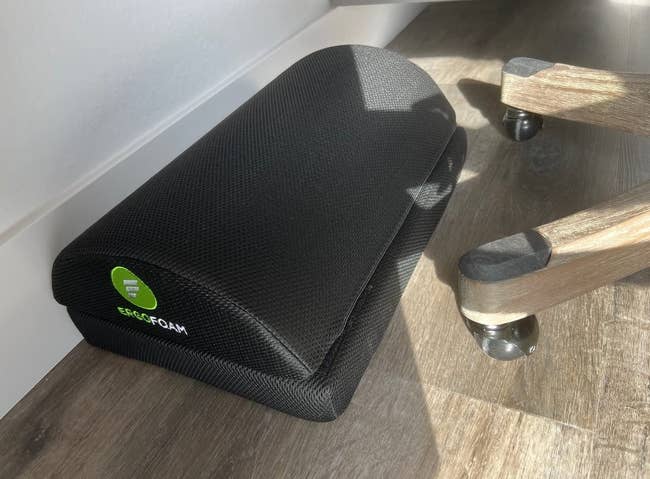 a reviewer photo of the foot rest in blackunder a desk 