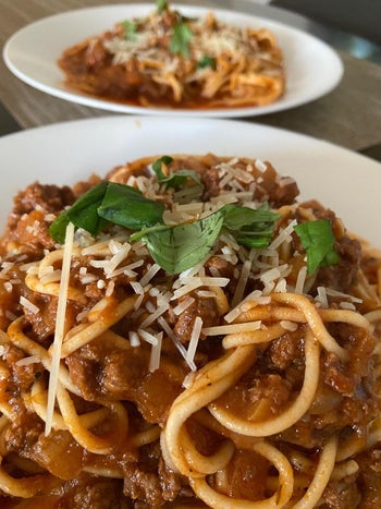 reviewer photo of two plates of homemade spaghetti with a tomato meat sauce