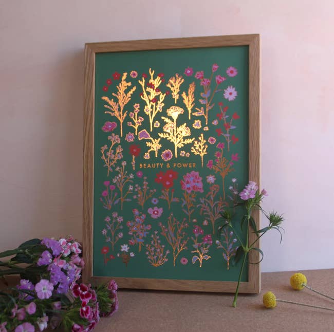 Green print with flowers and gold foil shimmering in the light framed in a wooden fram