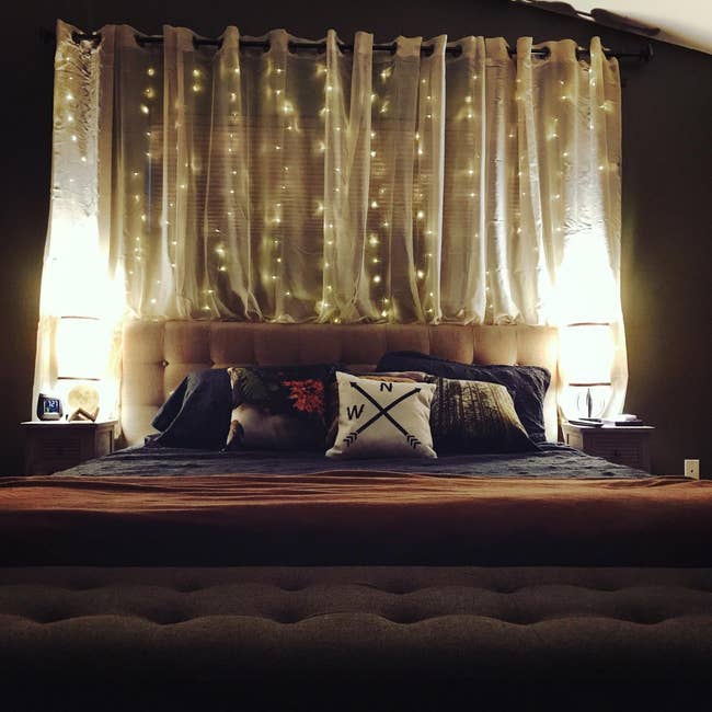 a reviewer's photo of the twinkle lights hanging behind their bed