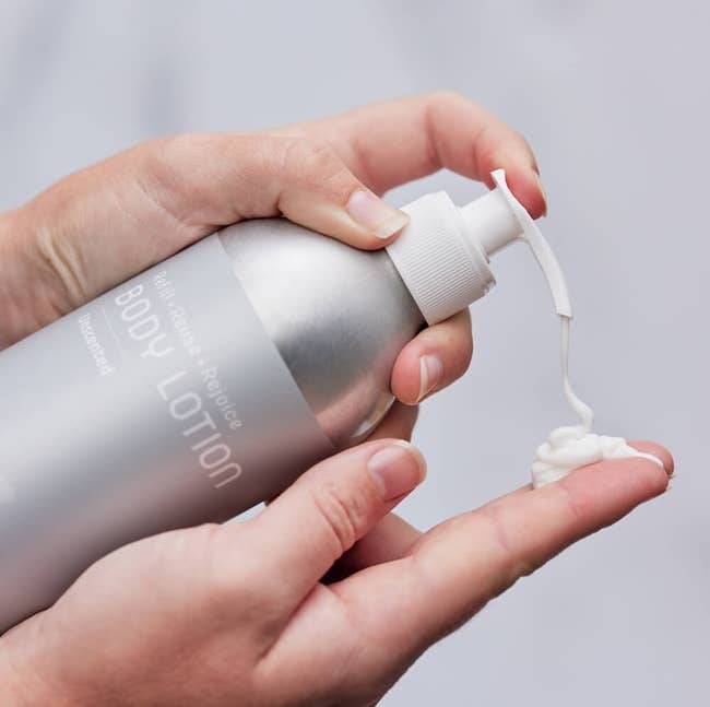 a model squirting lotion into their hand from an aluminum bottle 