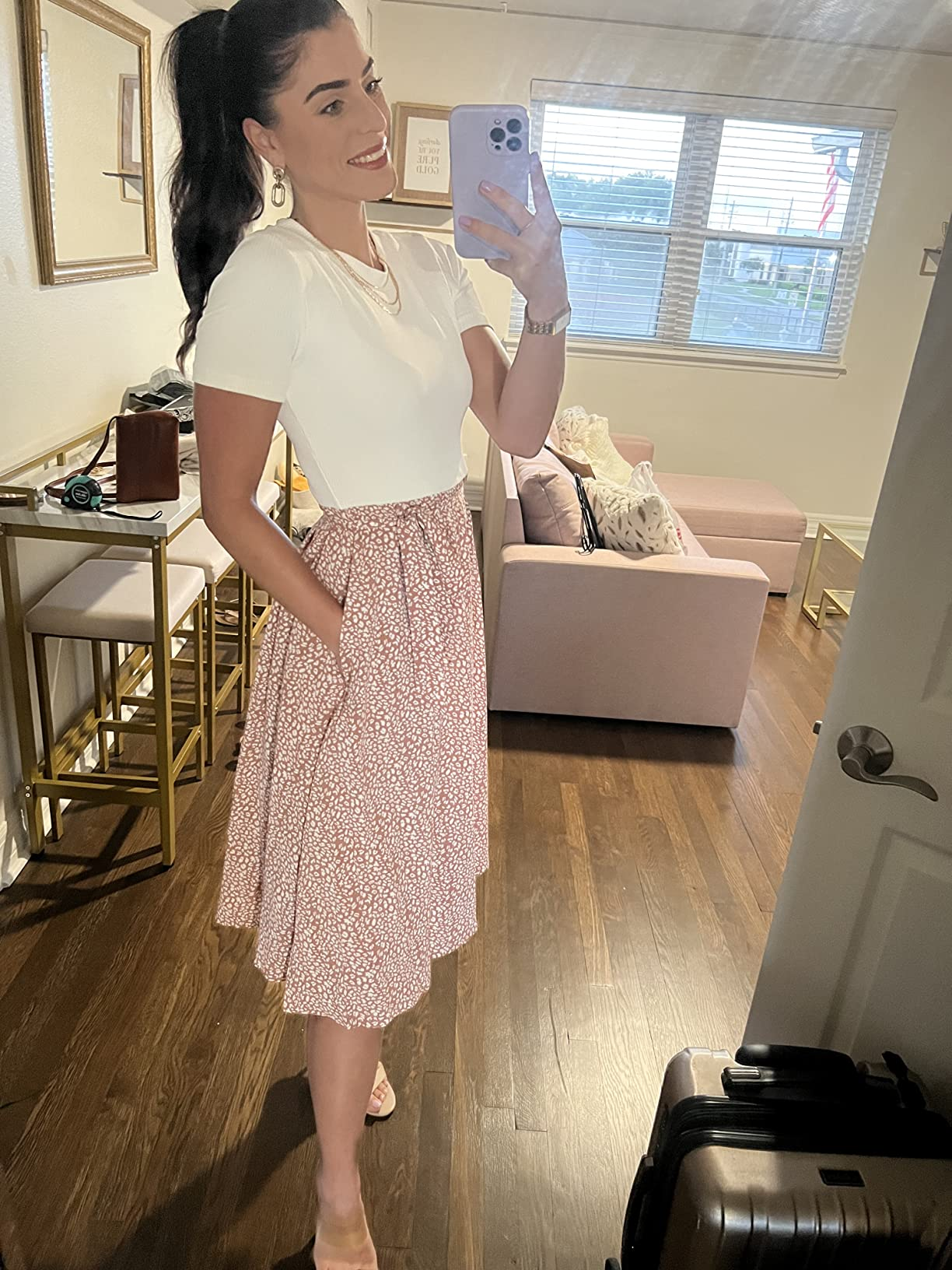Person successful  a achromatic  apical  and patterned skirt takes a reflector  selfie successful  a stylish surviving  room; luggage visible, hinting astatine  question   oregon  shopping
