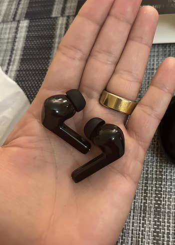 Person holds a brace  of wireless earbuds