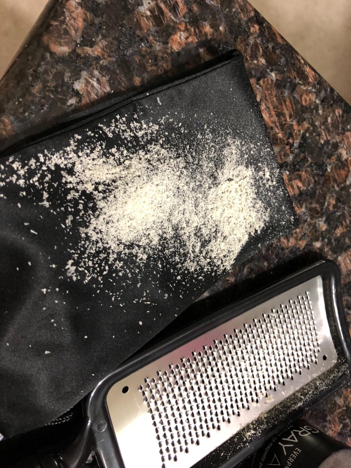 reviewer photo of the foot rasp next to a pile of dry skin flakes the rasp removed from their feet