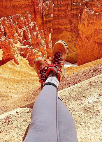 reviewer with boots on hanging over a canyon
