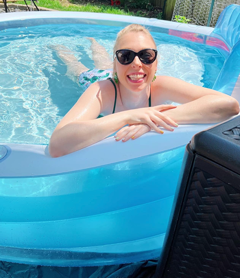 Reviewer leaning on the edge of the round blue inflatable pool 