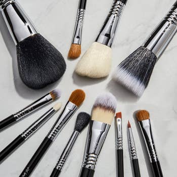 Assorted makeup brushes laid out on a marble surface, suitable for various beauty applications