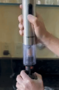 Person using a cordless, handheld wine opener to open a bottle 