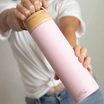 a model holding a pink water bottle by the hooked cap 