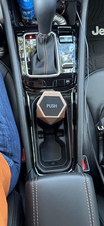 reviewer's small trash can in the cup holder in their car