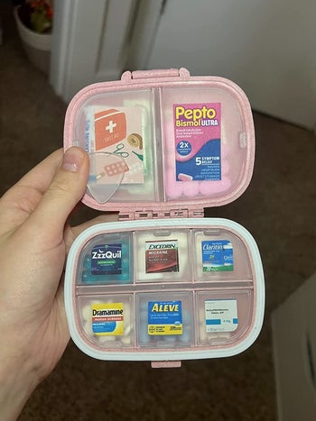 Reviewer holding their pink pill organizer filled with pills and with the compartments labeled 