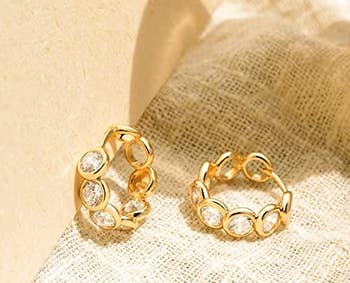 gold tone small hoop earrings with circular gems all around