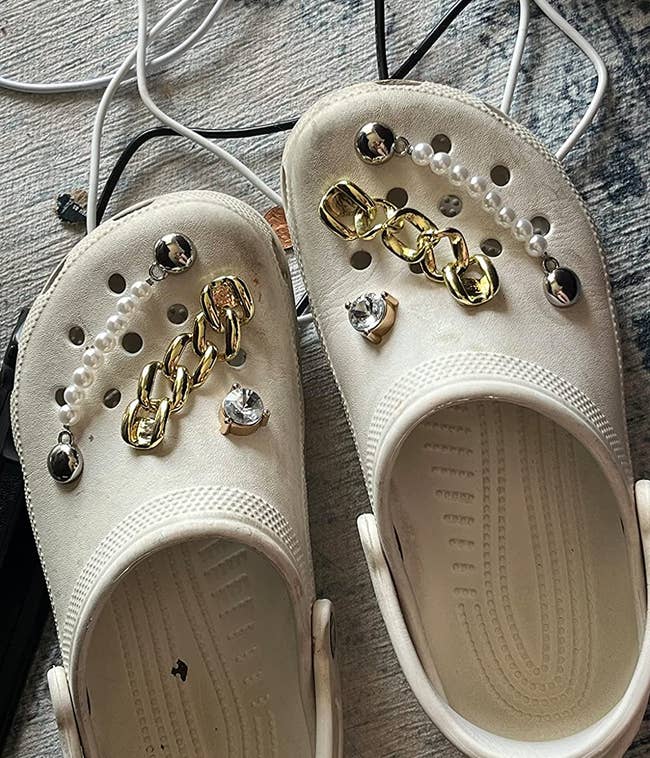 reviewer's  off white crocs shoes embellished with rhinestone charm, chain link strap and pearl strap across holes