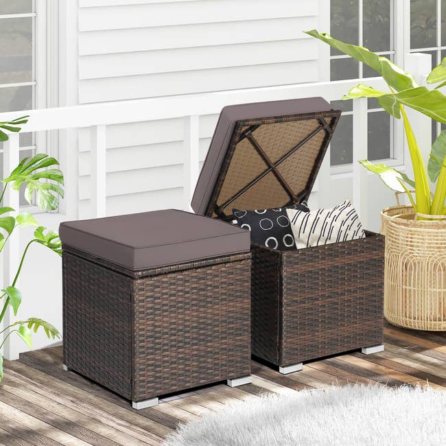 Two wicker retention  ottomans with removable cushions connected  a patio, 1  showing interior with patterned pillows, amid tropical plants