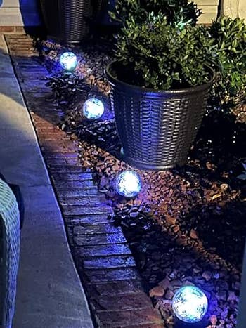 Garden way with decorative glowing orb lights acceptable on the crushed beside potted plants