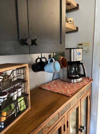 reviewer photo of mugs on hooks under the kitchen cabinet