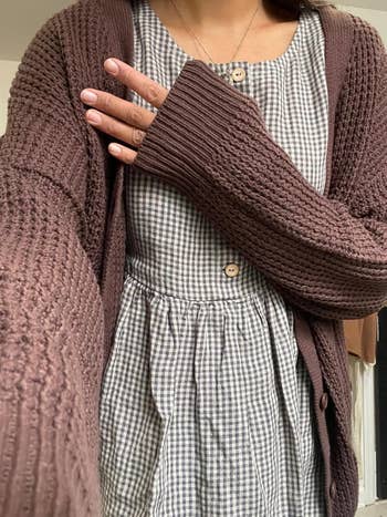 Person wearing a checkered formal  and textured cardigan, showcasing cozy autumn  manner  suitable for shopping