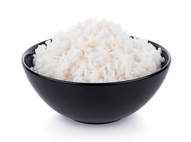 A black bowl filled with cooked, fluffy white rice