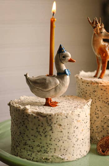 a ceramic goose atop a barroom   holding a lit candle