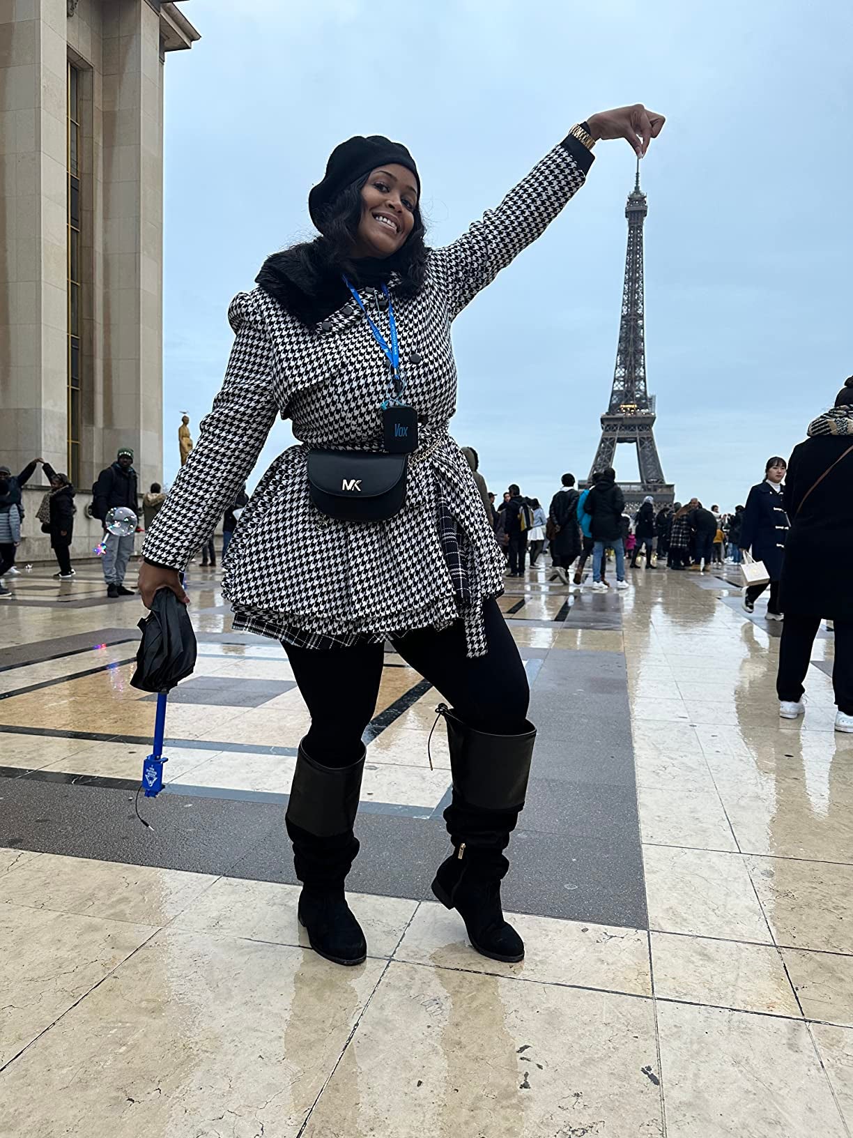 reviewer in houndstooth belted coat standing in front of the eiffel tower