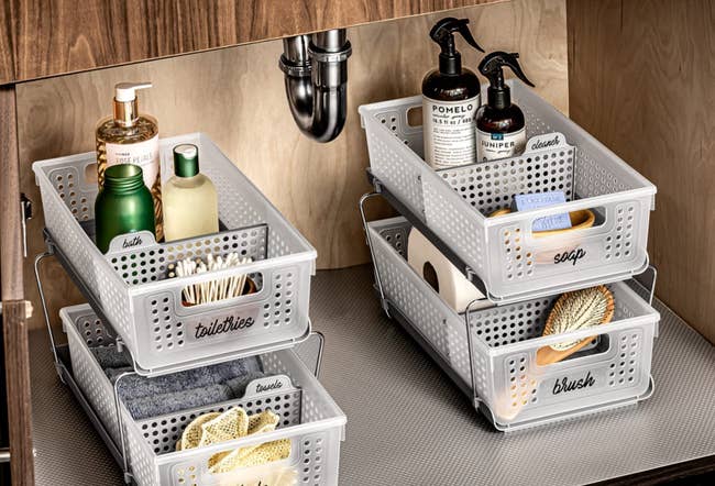 the baskets under a sink cabinet filled with bathroom products