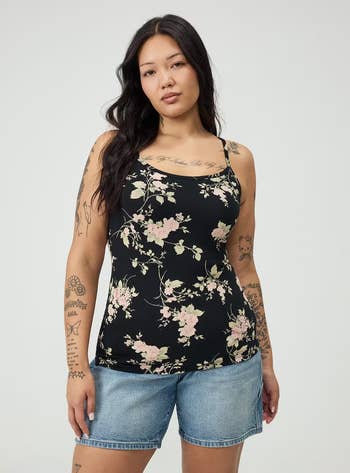 Person wearing a floral cami and denim shorts, showcasing casual style