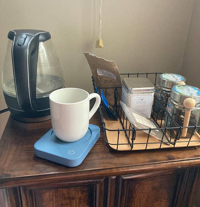 A mug sitting on the blue warmer on a reviewer's coffee table