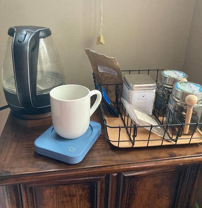 A mug sitting on the blue warmer on a reviewer's coffee table