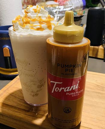 reviewer photo of the bottle of pumpkin pie sauce next to a drink topped with whipped cream and the sauce