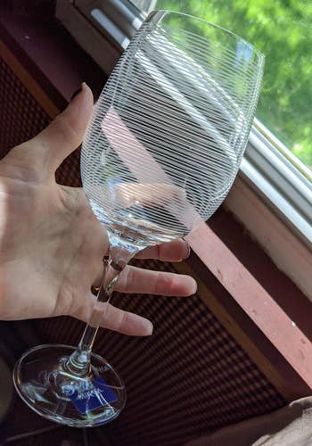 Reviewer holding striped wine glass