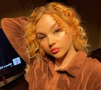 Person with curly hairsbreadth poses successful a stylish velvety blouse wrong a room. A TV successful the inheritance displays a black-and-white face