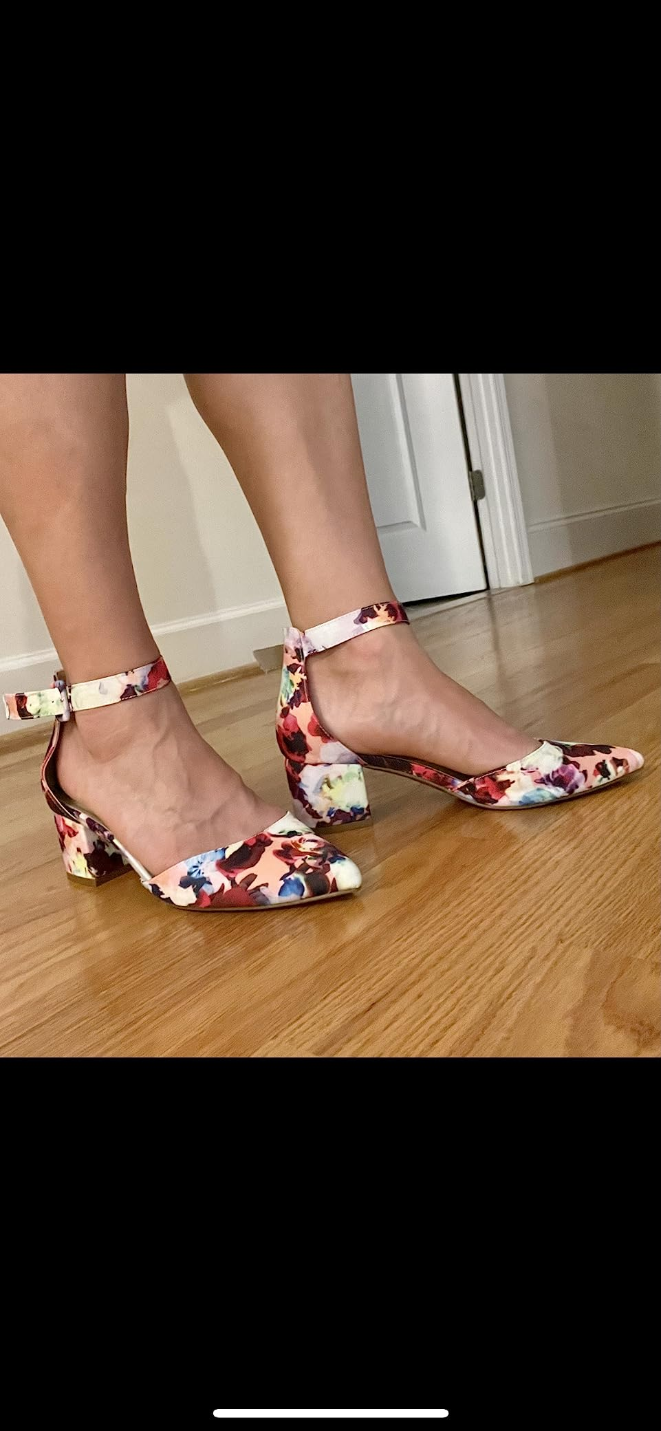 Person wearing floral-patterned block-heeled shoes with ankle straps connected  a woody  floor