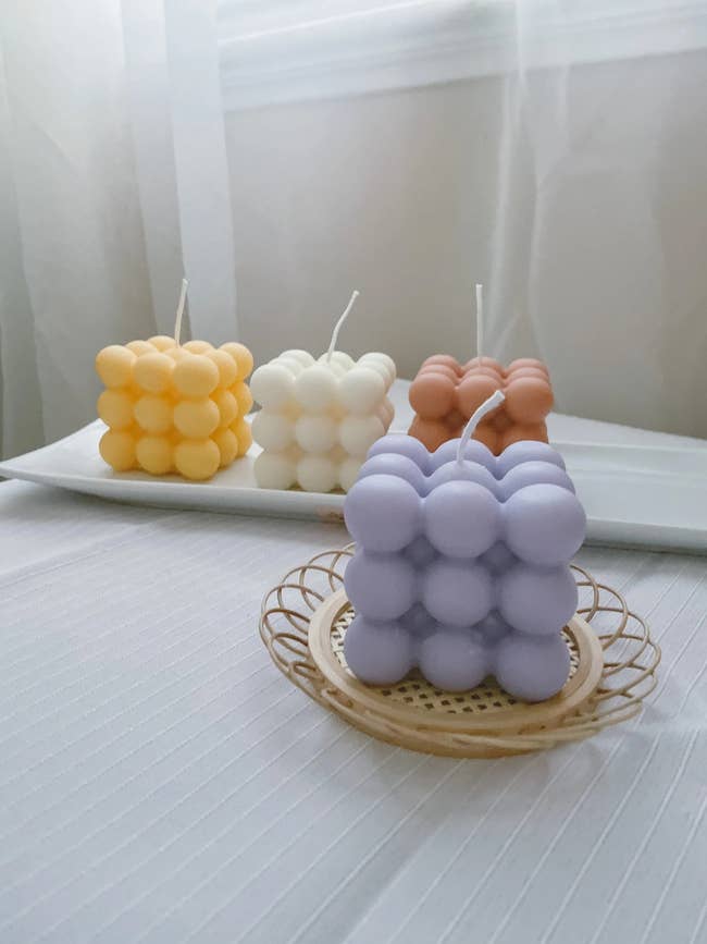 a purple, yellow off white, and orange bubble candle