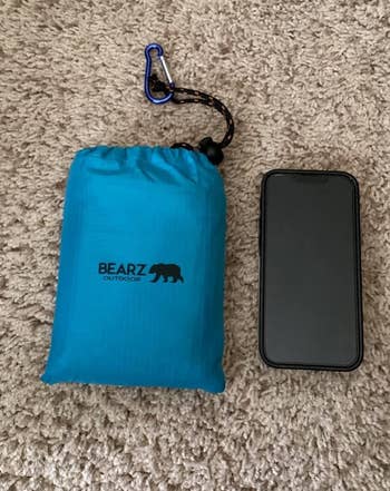 BEARZ Outdoor compact blue bag with carabiner next to a smartphone on carpet