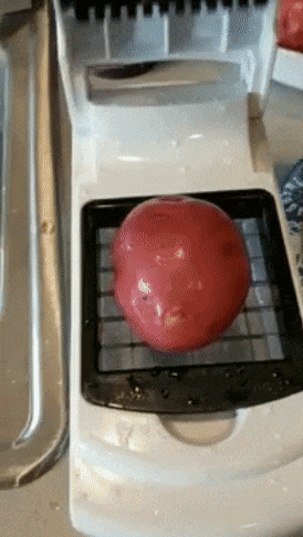 Reviewer striking a potato on a flip high lid cutter and bringing the lid down to gash it into items 