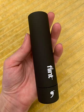 a reviewer's hand holding the retractable travel lint roller
