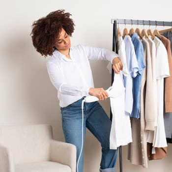 a model using the nori press to iron a hanging garment