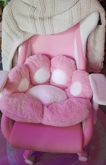 reviewer photo of a pink cat paw cushion with white pads on a pink gaming chair