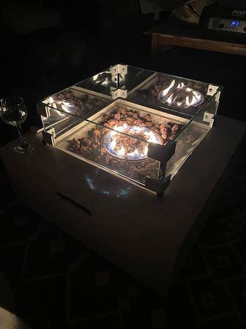 a reviewer's square fire pit lit up at night with a guard around it